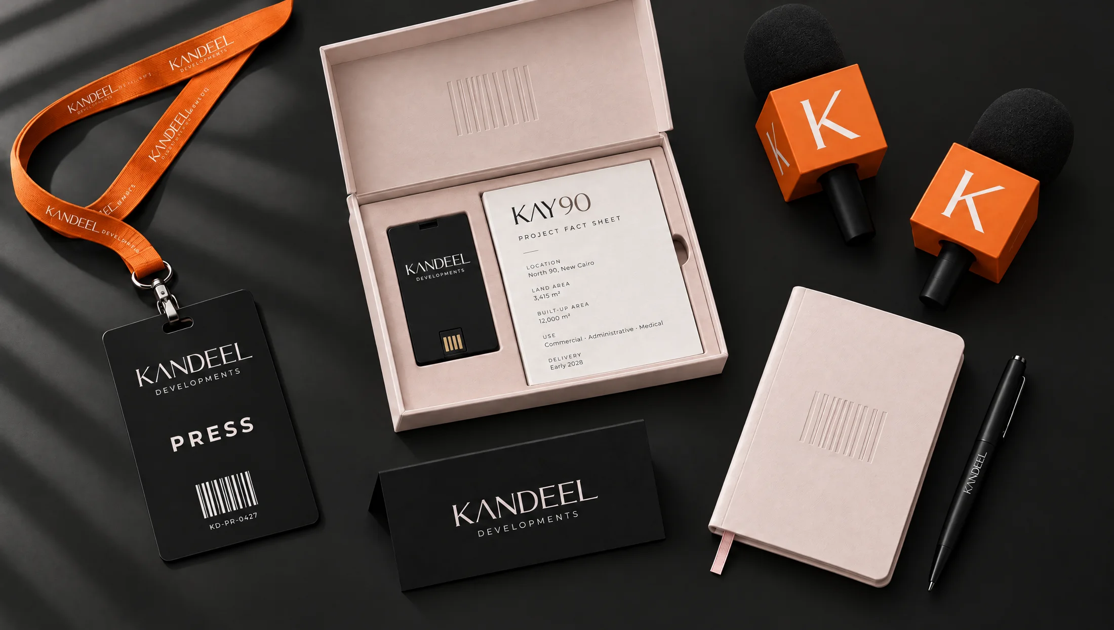 Press kit flat-lay: badge on orange lanyard, Dawn Pink press box, mic flags, name tent