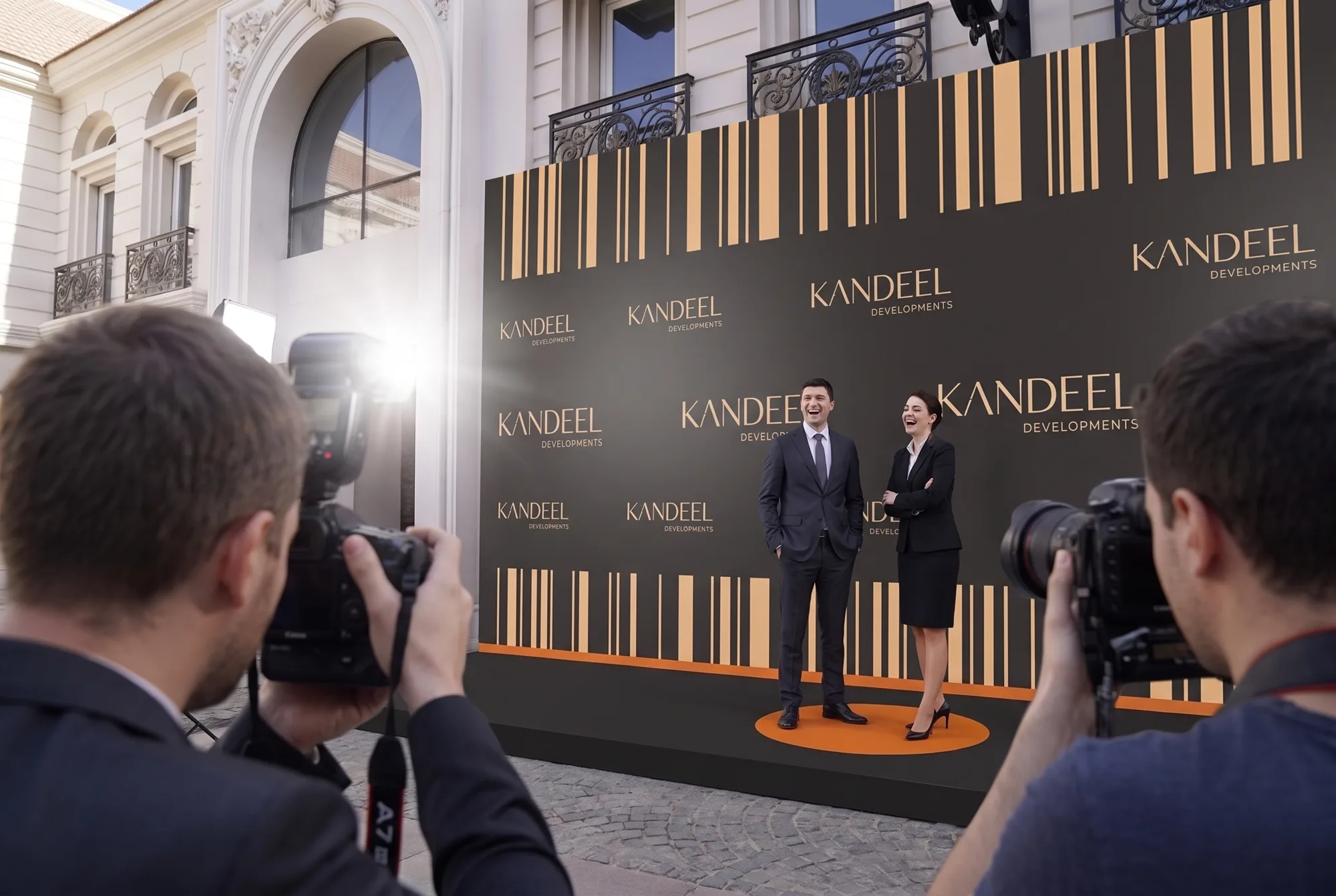 Press photographers shooting guests at the Kandeel Developments step-and-repeat photo wall in the courtyard